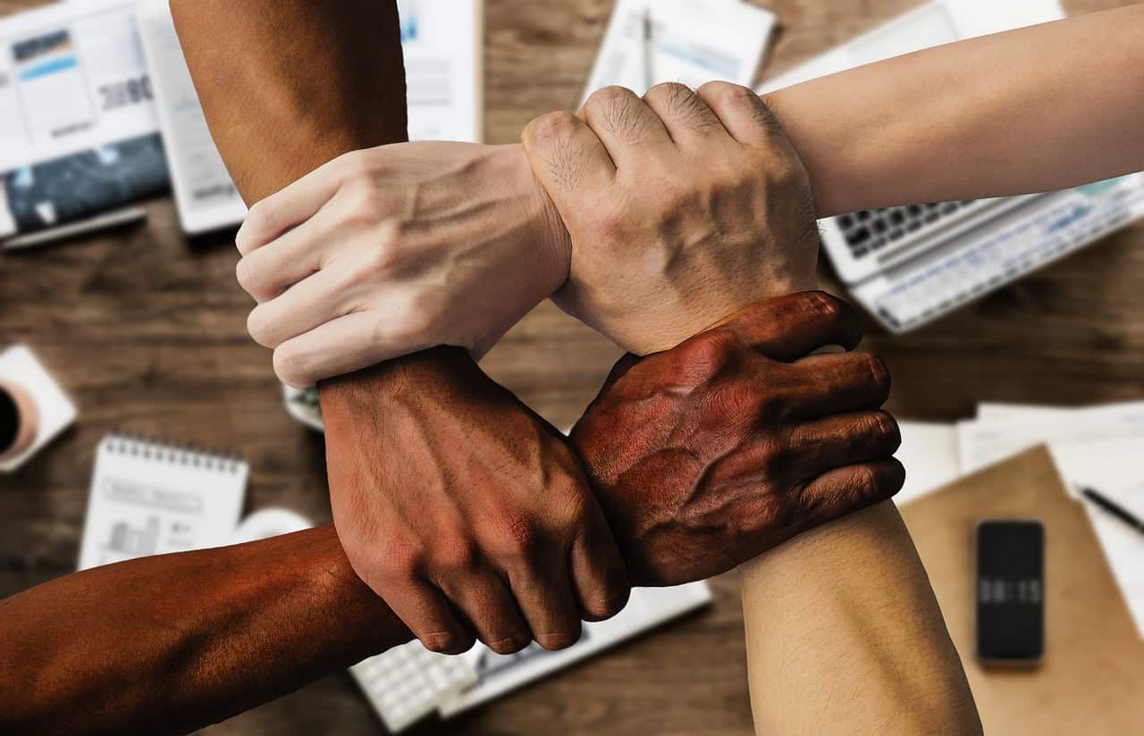 four hands linked togther supporting at the wrist